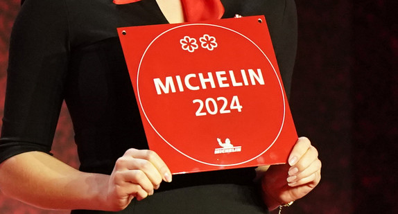 Eine Frau hält eine Michelin-Plakette während der Verleihung der Michelin-Sterne 2024 hoch.